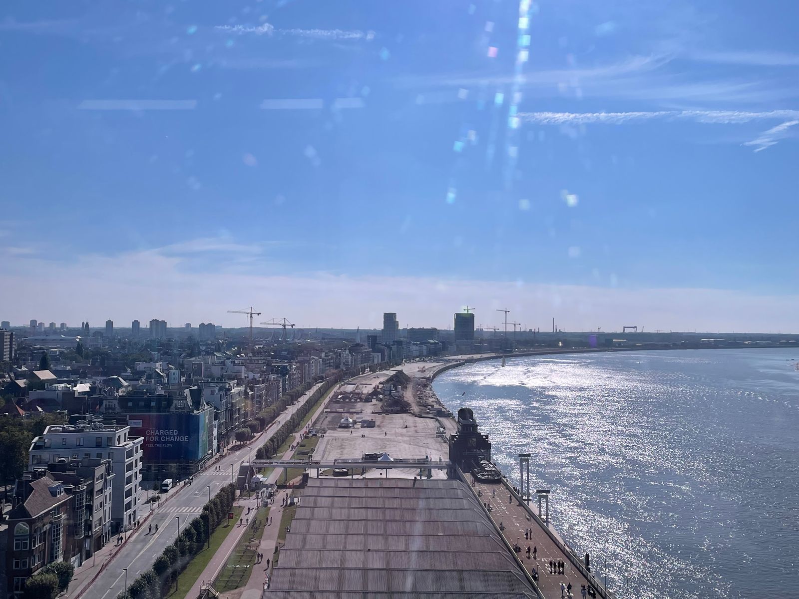 A high window along the Scheldt: the harbor, cranes, and sun glare on the water