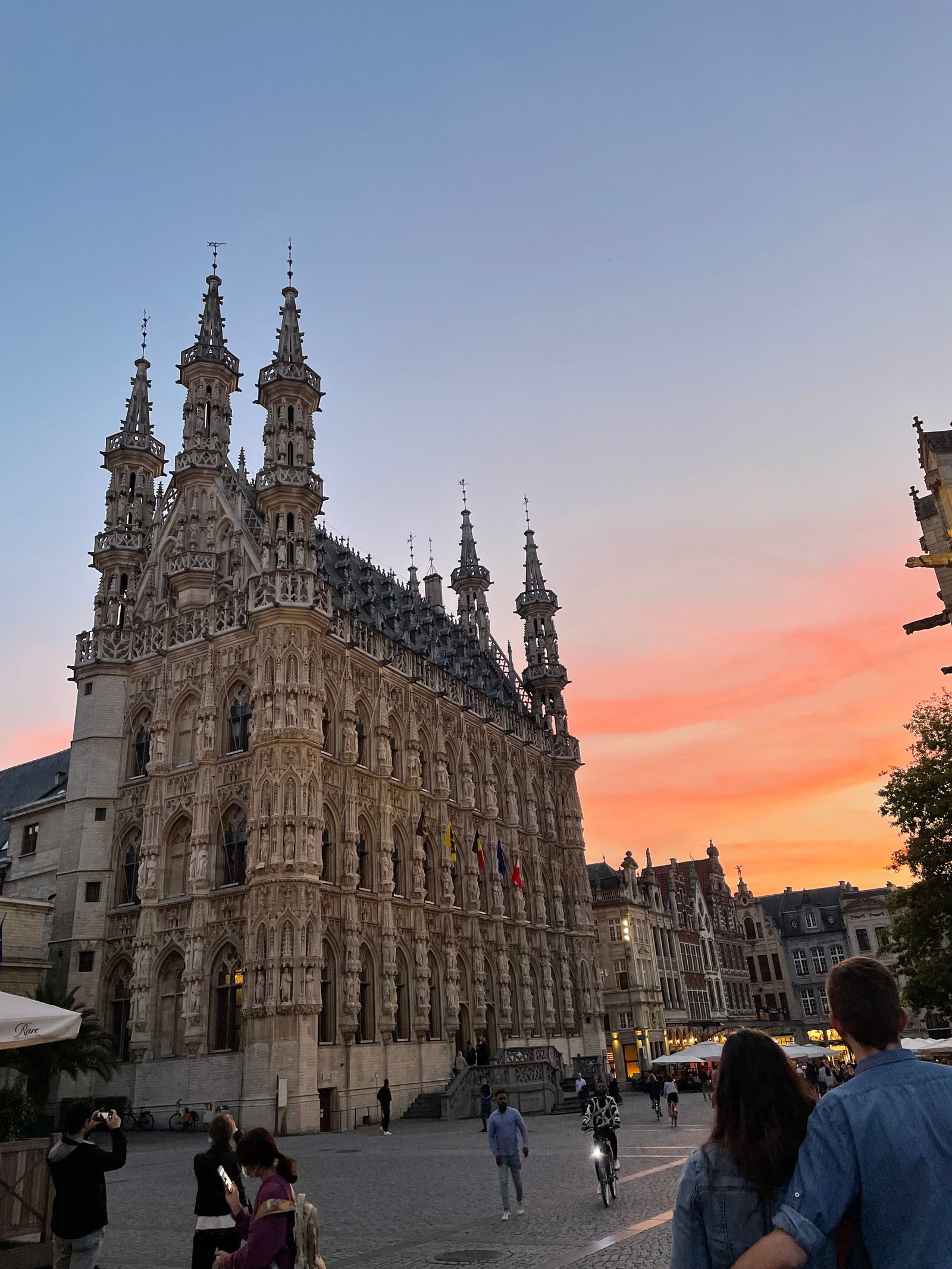 Leuven Town Hall on the Grote Markt at sunset, cobblestones and café umbrellas
