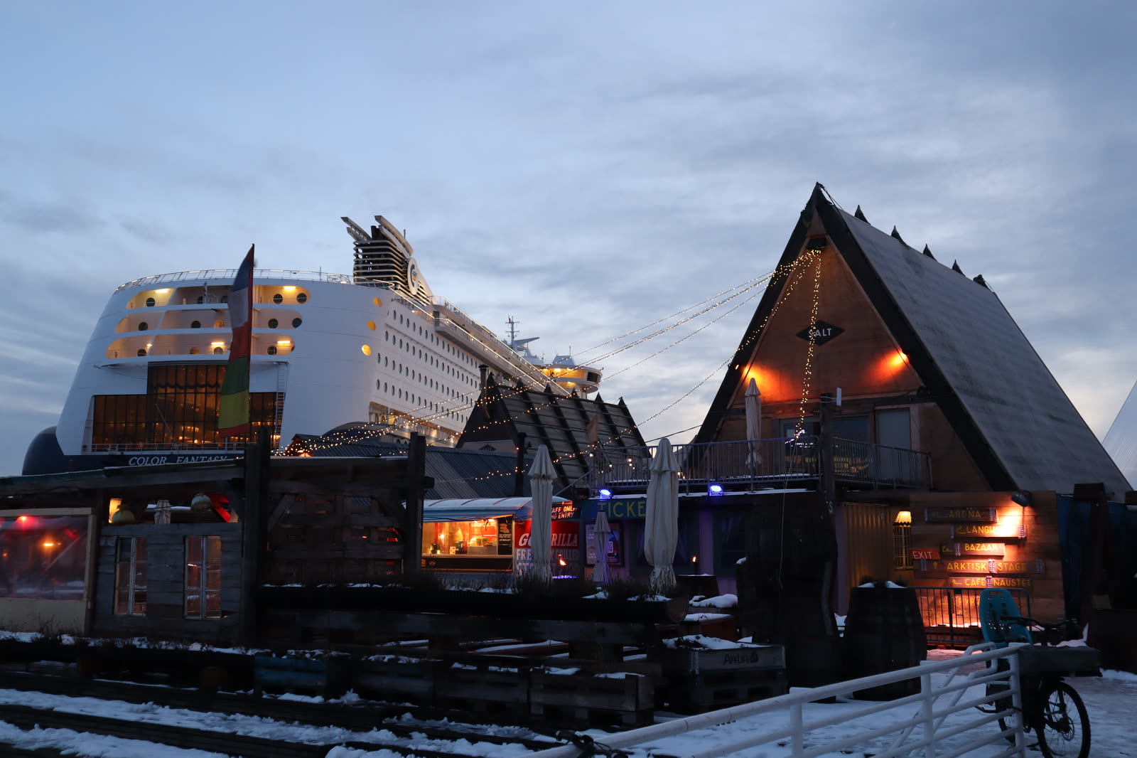 The Color Fantasy cruise ship beside the wooden SALT A-frame on a snowy harbor quay